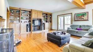 A spacious living area with a large wooden entertainment center, a grey sofa, and a black ottoman.