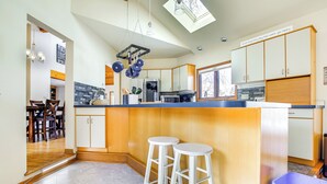 A modern kitchen with a central island, wooden cabinets, and a dining area with chairs.