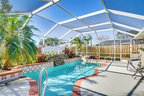 Relax by the clear pool surrounded by lush tropical plants and a shaded canopy.