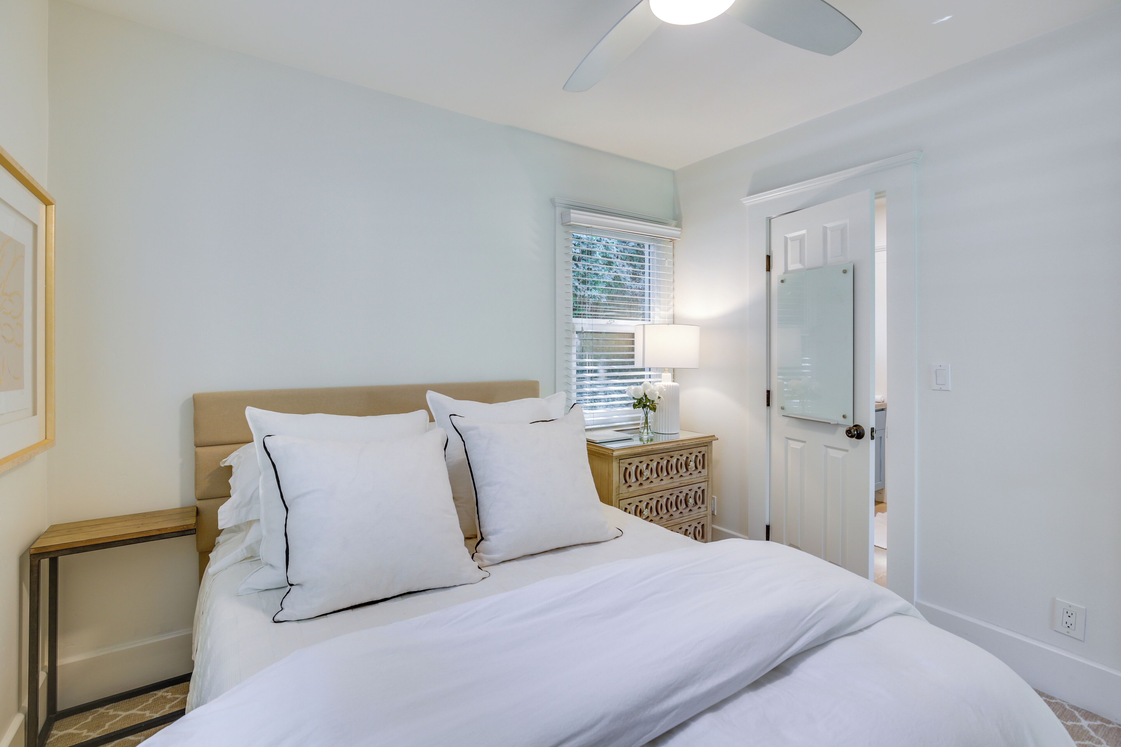 A bedroom with a bed, bedside table, lamp, and a door.