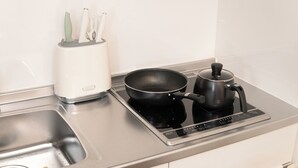 A kitchen with a stainless steel sink, a black frying pan on an induction cooktop, and a white toaster. - Numabuki New Boutique Cozy Apartment，Private Bathroom ，High-quality Bedding (中野区沼袋)