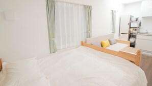A bedroom with a bed, a wooden headboard, a small table, and a window with curtains. - Numabuki New Boutique Cozy Apartment，Private Bathroom ，High-quality Bedding (中野区沼袋)