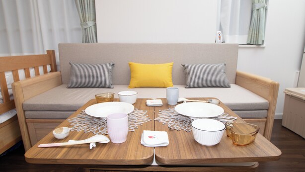 A neatly arranged dining area with a wooden table set for four, a sofa with cushions, and a window with curtains. - Numabuki New Boutique Cozy Apartment，Private Bathroom ，High-quality Bedding (中野区沼袋)