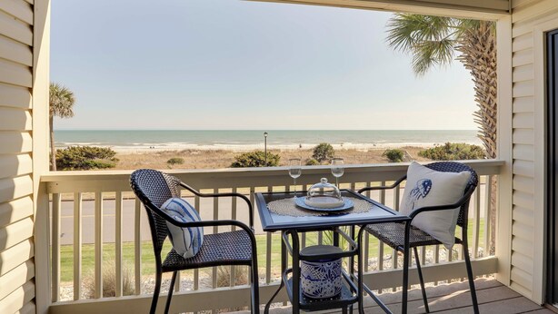 A balcony with a table and chairs overlooking a beach. - Scenic Oceanfront Condo in Myrtle Beach! (Myrtle Beach)