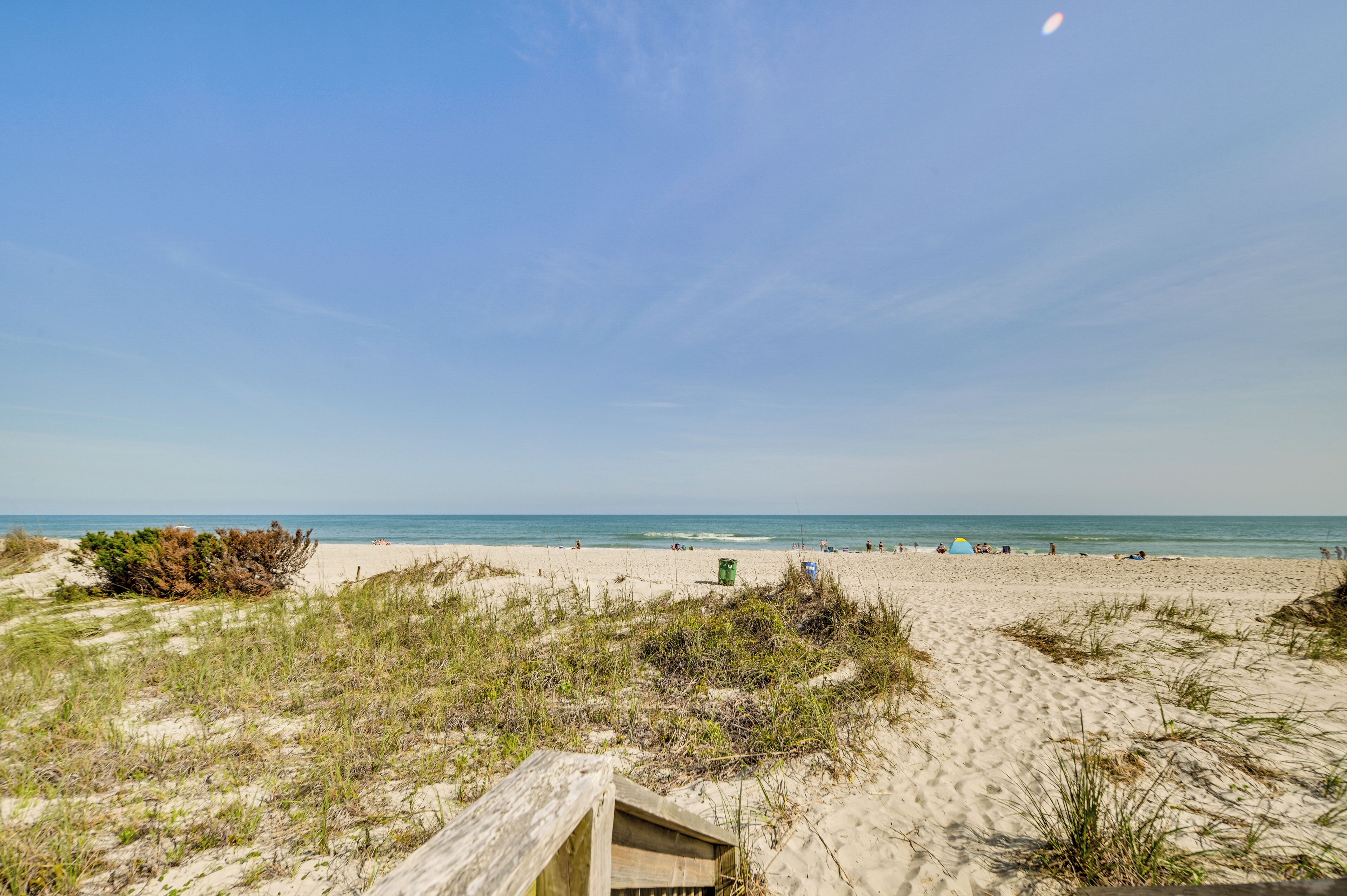A sandy beach with dunes and a wooden structure.