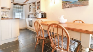 A kitchen with white cabinets, a wooden dining table, and two patterned chairs.