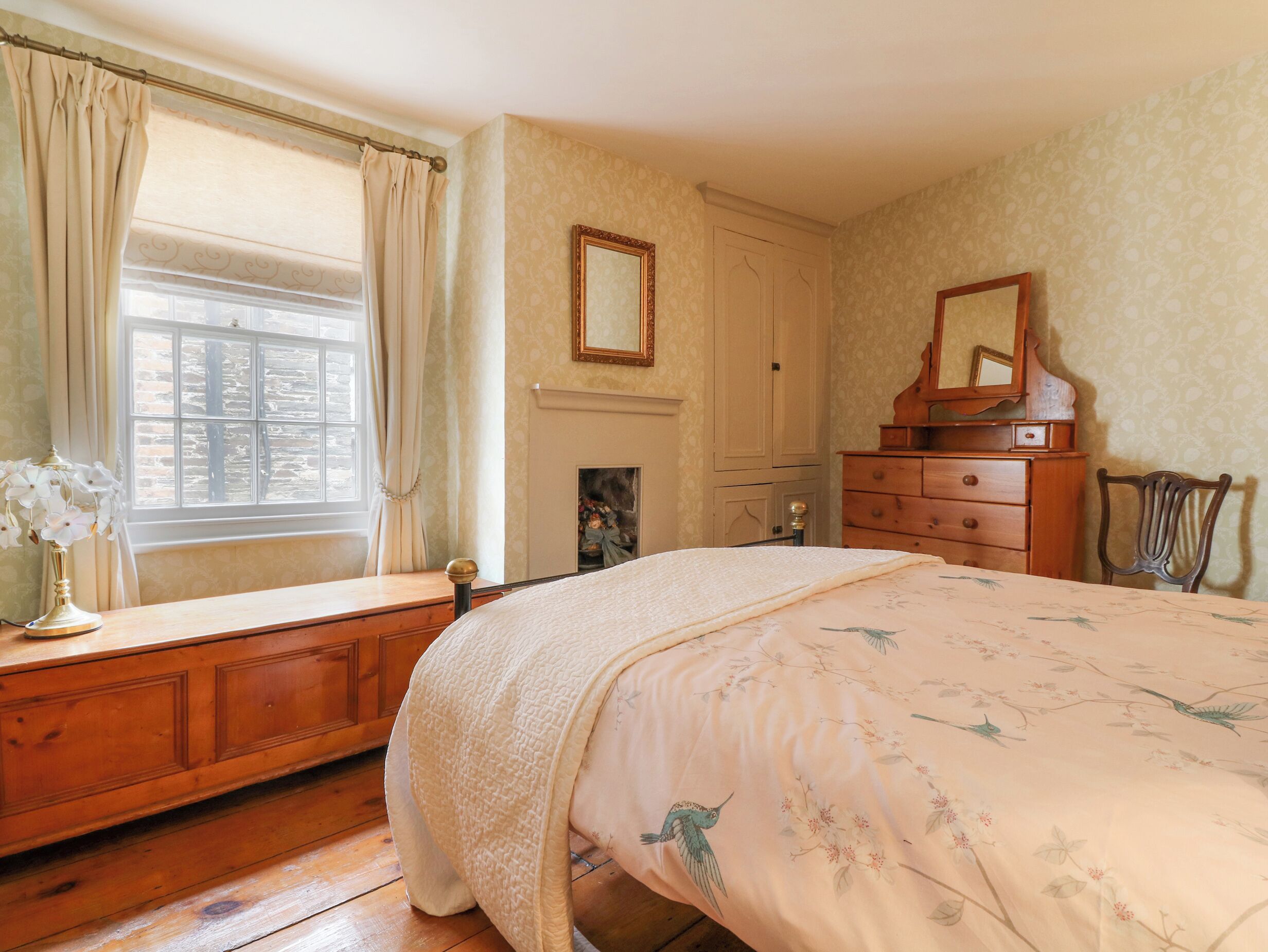 A bedroom with a large bed, wooden dresser, and a mirror.