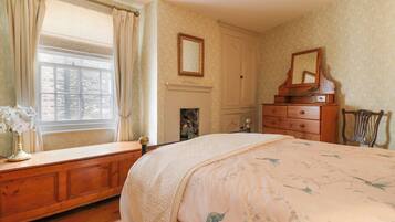 A bedroom with a large bed, wooden dresser, and a mirror.