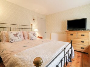 Un dormitorio con cama, cómoda, televisor y mesita de noche.