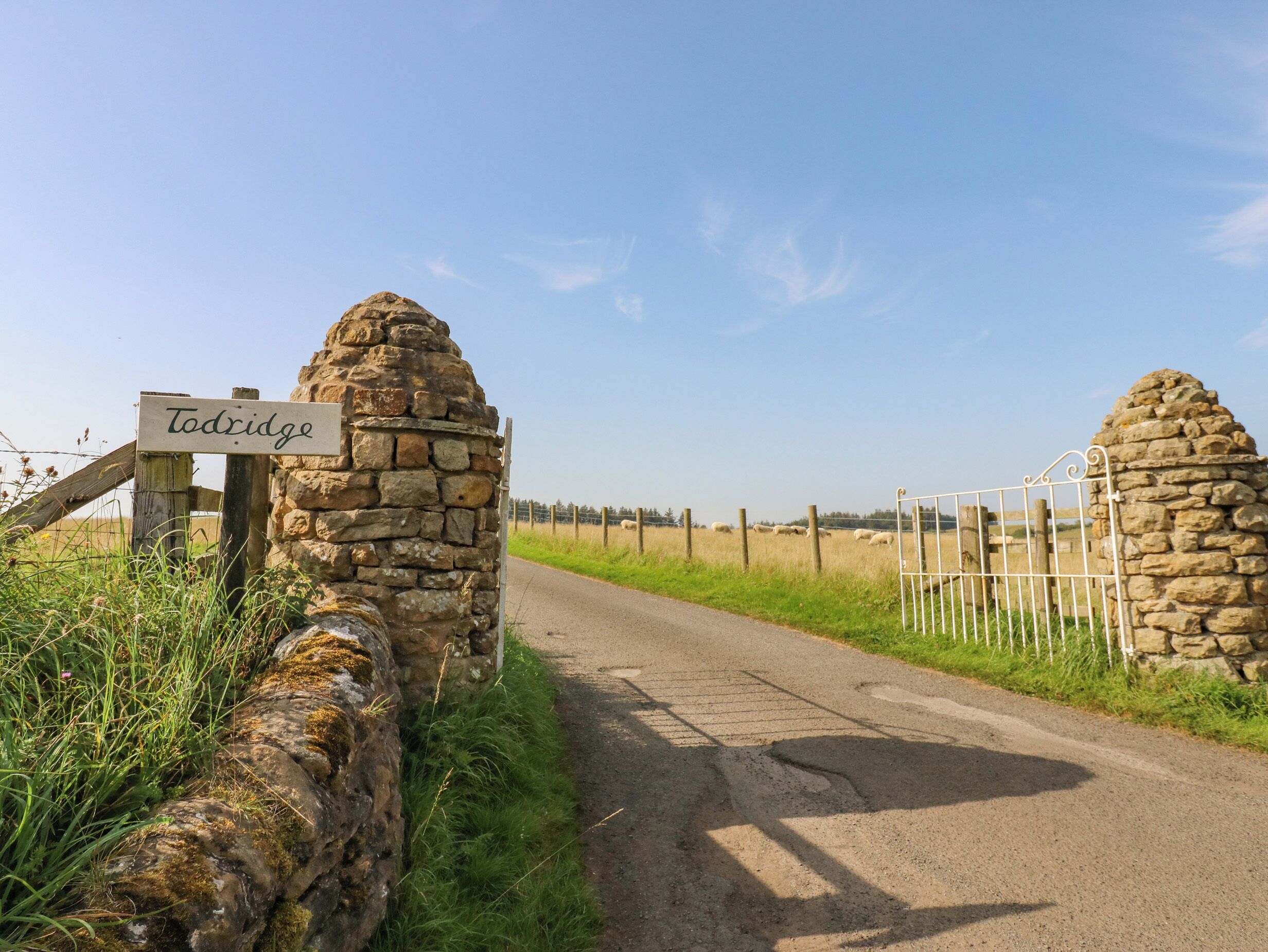 A rural road with a stone gate and a sign reading "Todridge."