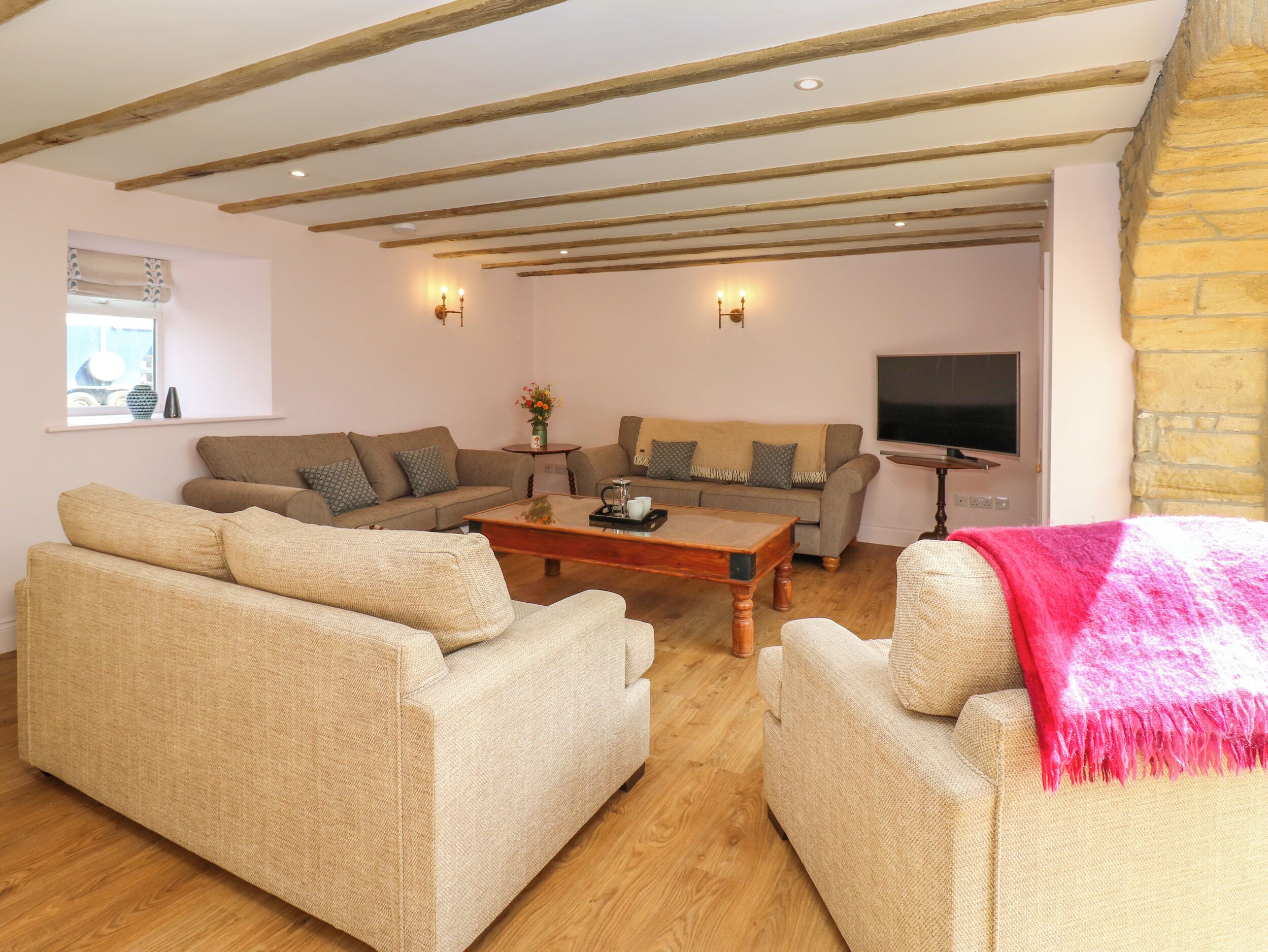 A cozy living room with a wooden ceiling, two sofas, a coffee table, and a TV.