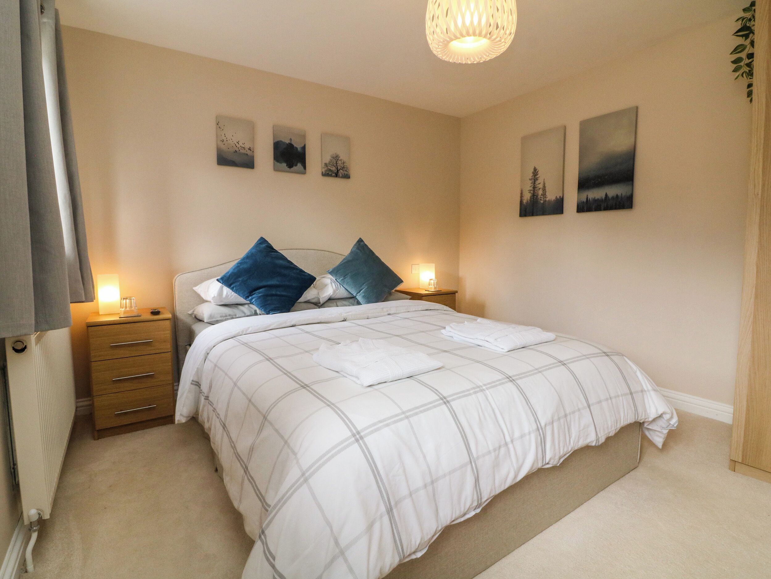 A neatly arranged bedroom with a bed, bedside tables, and wall art.