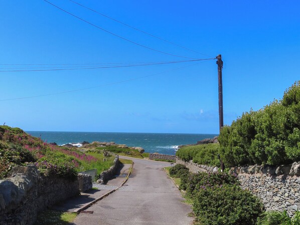 A coastal road with a stone wall on one side and a utility pole on the other. - Seaside Sanctuary (Holyhead)