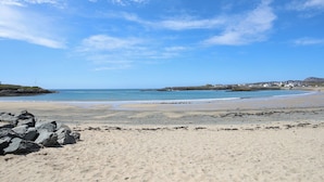 A beach with clear skies, calm waters, and a distant shoreline with buildings. - Seaside Sanctuary (Holyhead)