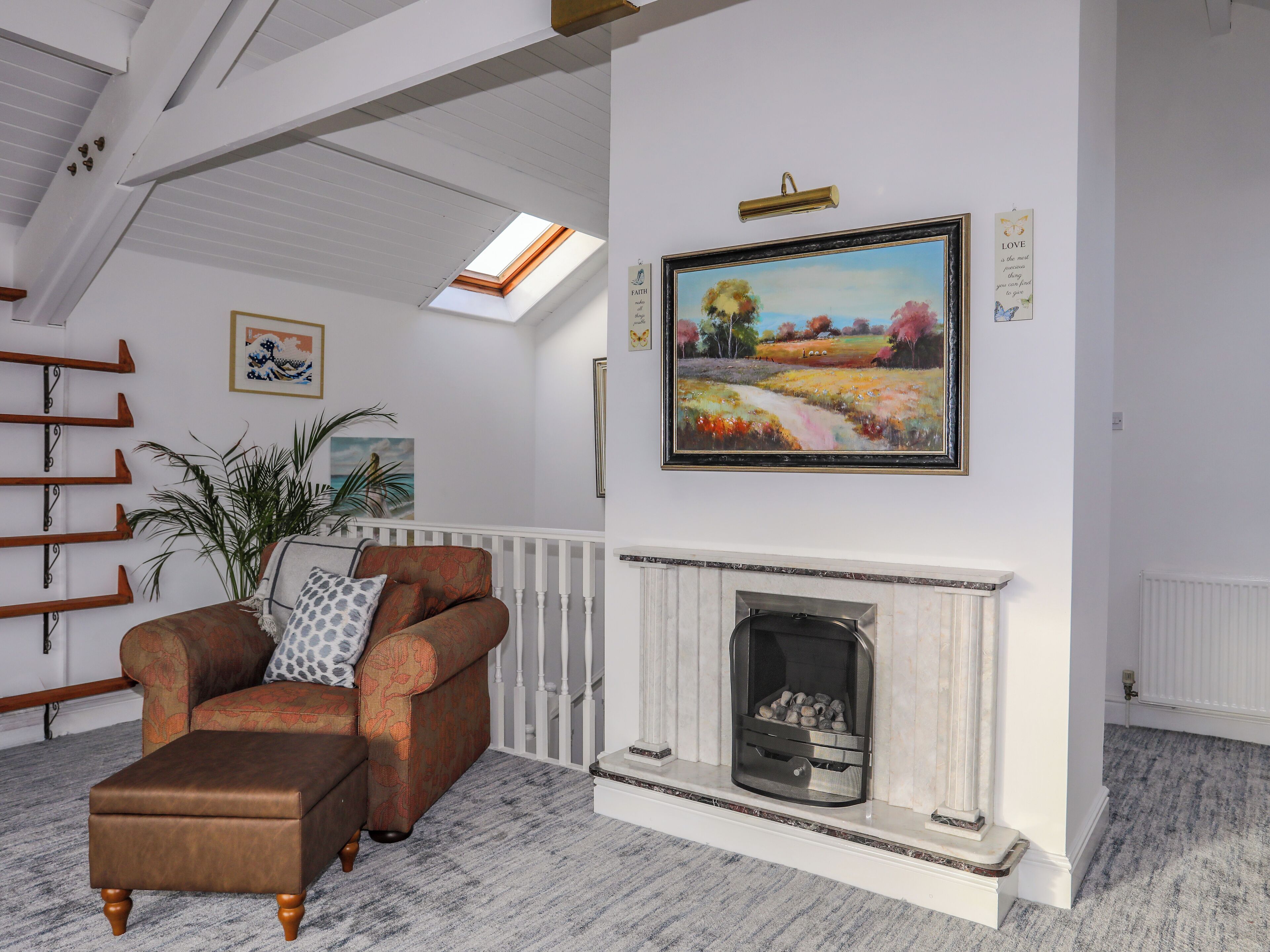 Un salon avec une cheminée, un canapé, une plante et un tableau au mur.