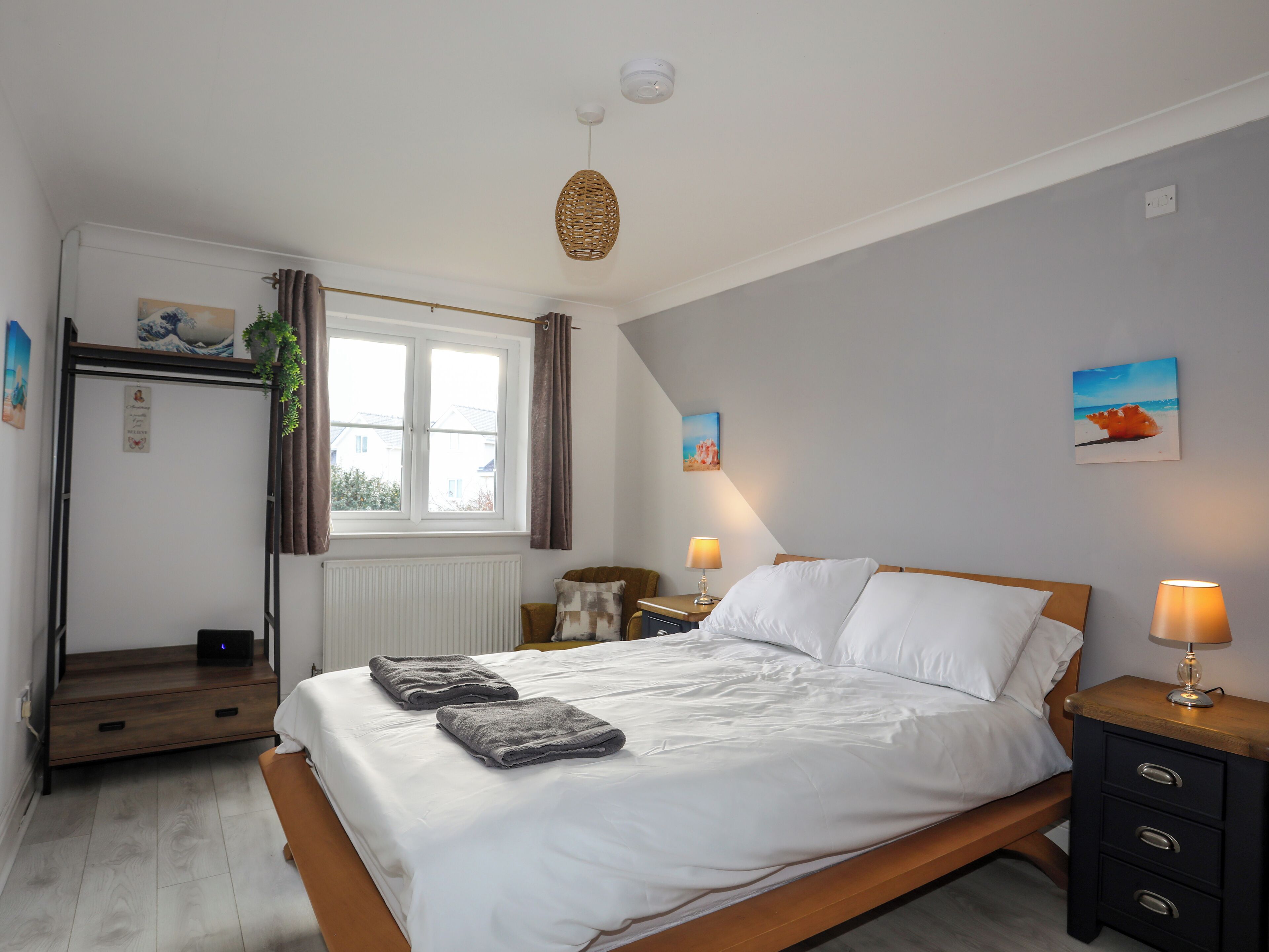 A bedroom with a bed, bedside tables, a window, and a radiator.