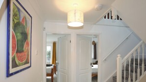 A hallway with a staircase, a framed artwork, and a door leading to a bedroom. - Seaside Sanctuary (Holyhead)