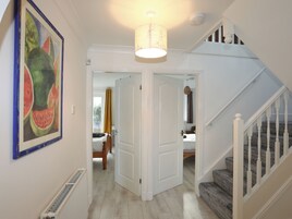 Un pasillo con una escalera, una obra de arte enmarcada y una puerta que da a un dormitorio.
