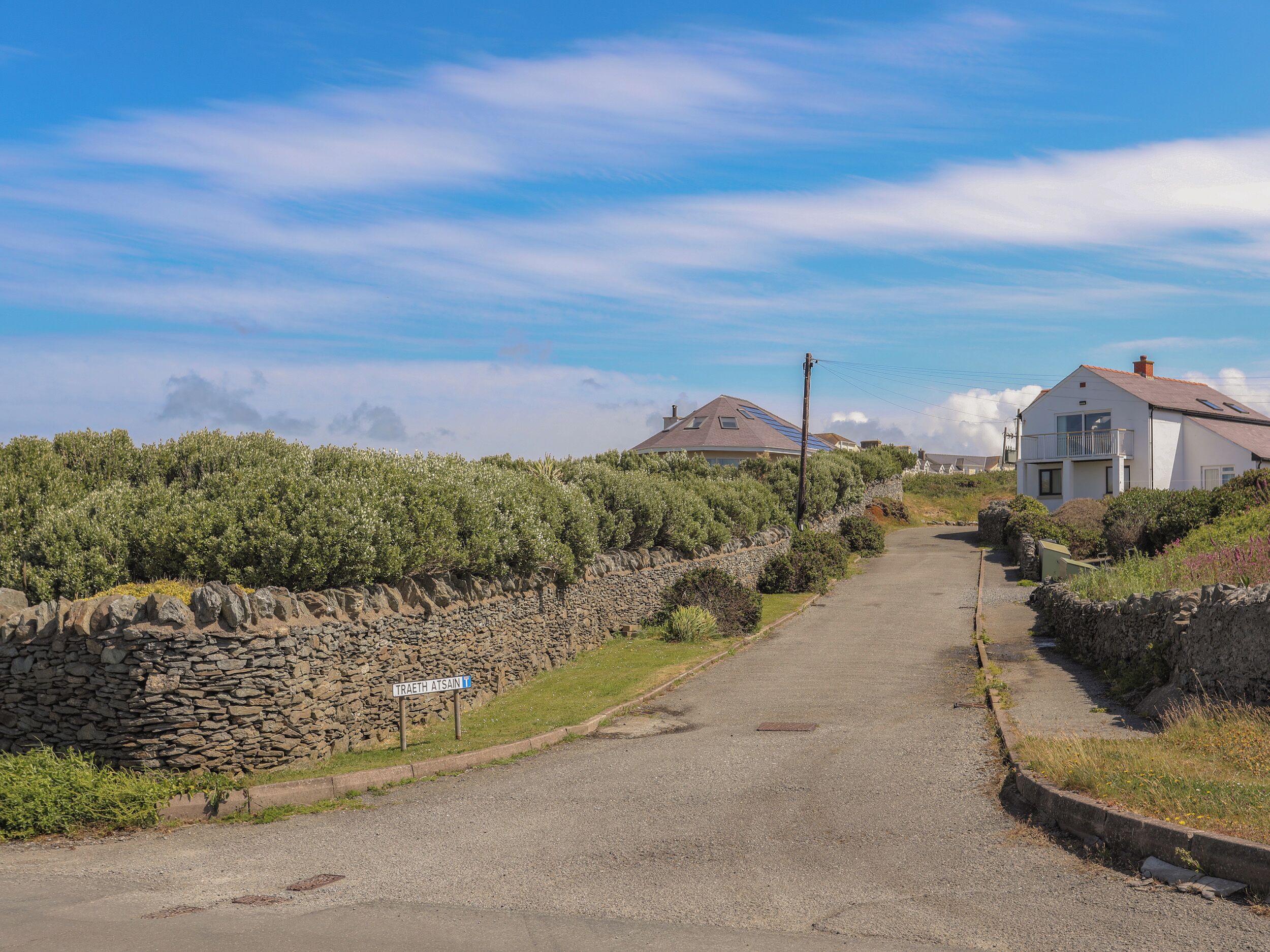 A rural road with stone walls and houses on either side.