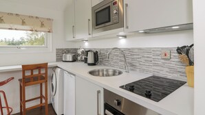 A modern kitchen with a microwave, toaster, coffee maker, and sink. - Mallard Lodge (Galston)
