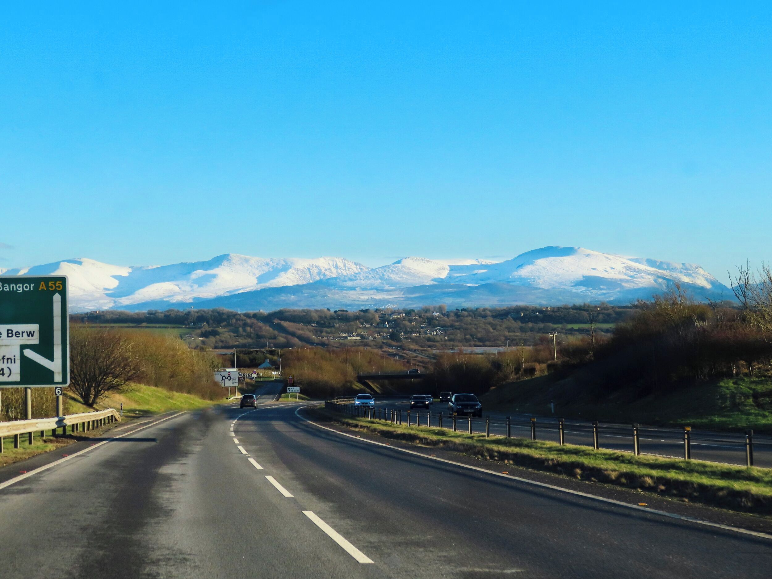 Una autopista con una señal de tráfico que indica direcciones a Bangor y Berw por la A55.