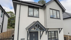 A two-story residential building with a dark front door, a small porch with a triangular roof, and a visible nameplate on the door.