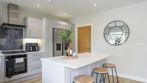 A modern kitchen with a central island, bar stools, a refrigerator, a stove, and a microwave.