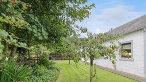 A well-maintained garden with a lawn, a tree, and a white building with a window. - The Barn at Daldorch (Mauchline)