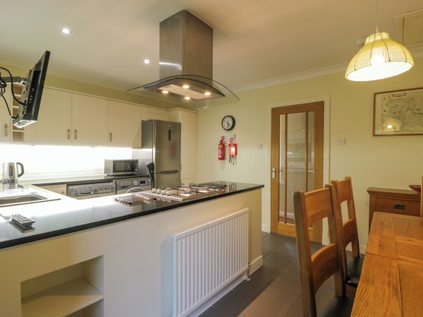 Una cocina moderna con una isla central, electrodomésticos integrados y un comedor con mobiliario de madera.