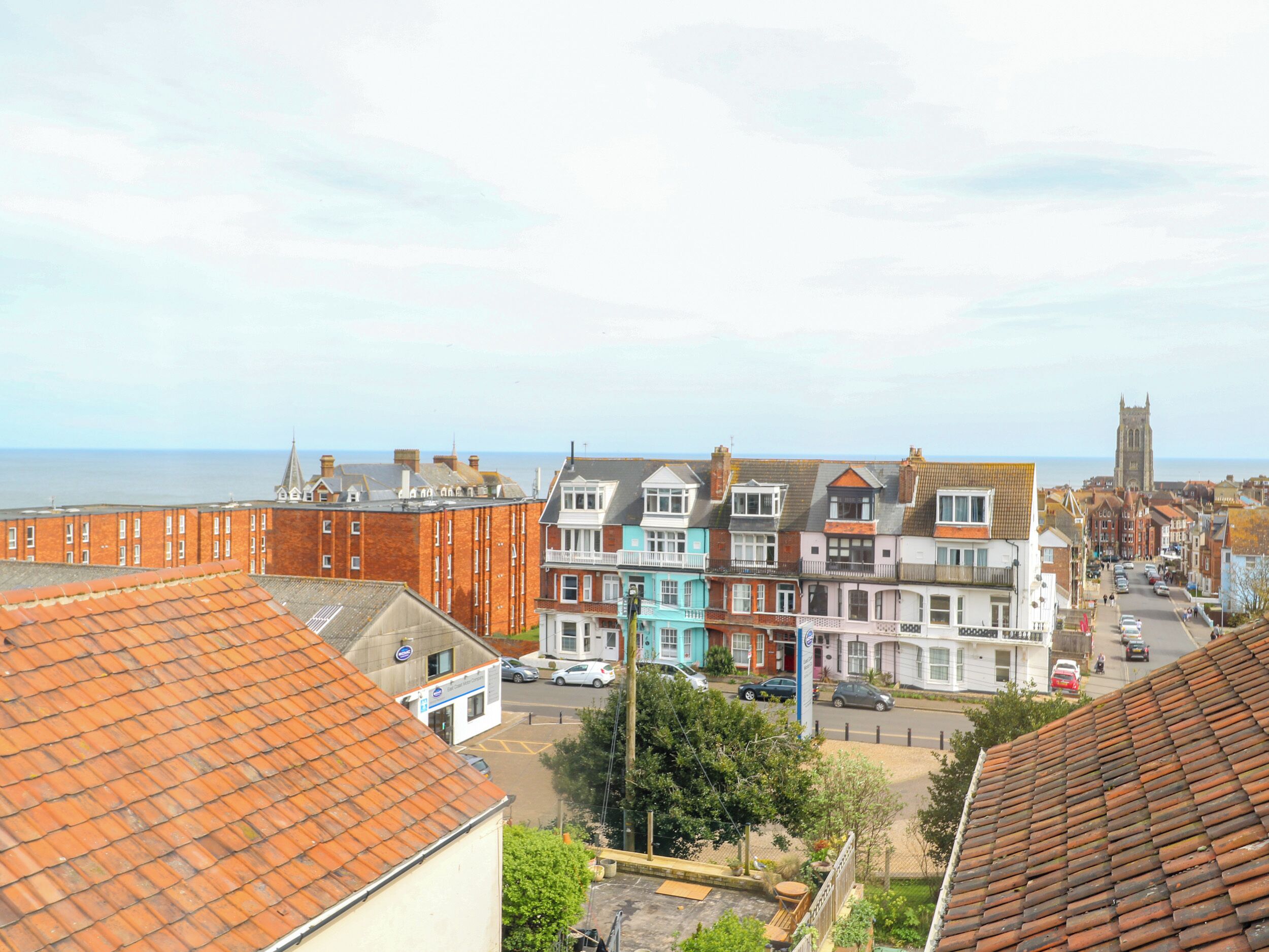 A coastal town with terracotta-tiled roofs, colorful buildings, and a prominent church tower in the distance.