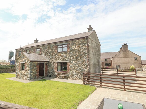 A stone house with a small front porch and a fenced yard. - Yr Hen Stabl (Caernarfon)
