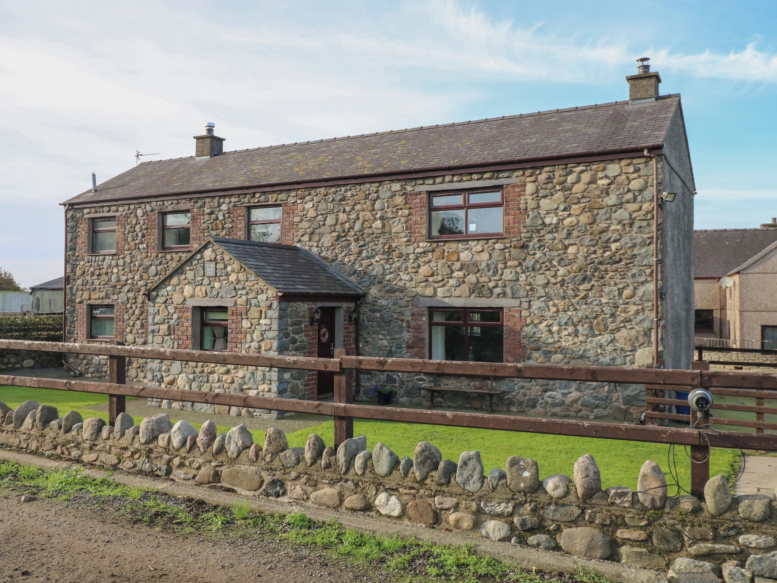 A stone house with a wooden fence in front.