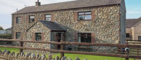 A stone house with a wooden fence in front.