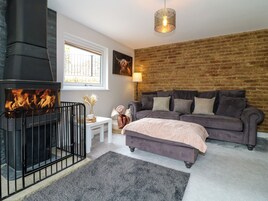 Una habitación acogedora con chimenea, pared de ladrillo, sofá gris y ventana.