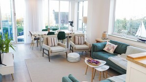 A modern living room with a sofa, chairs, a dining table, and a view of the outdoors. - Awel Y Mor (Prestatyn)