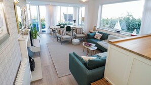 A modern living room with a sofa, chairs, a dining table, and a view of the outdoors. - Awel Y Mor (Prestatyn)