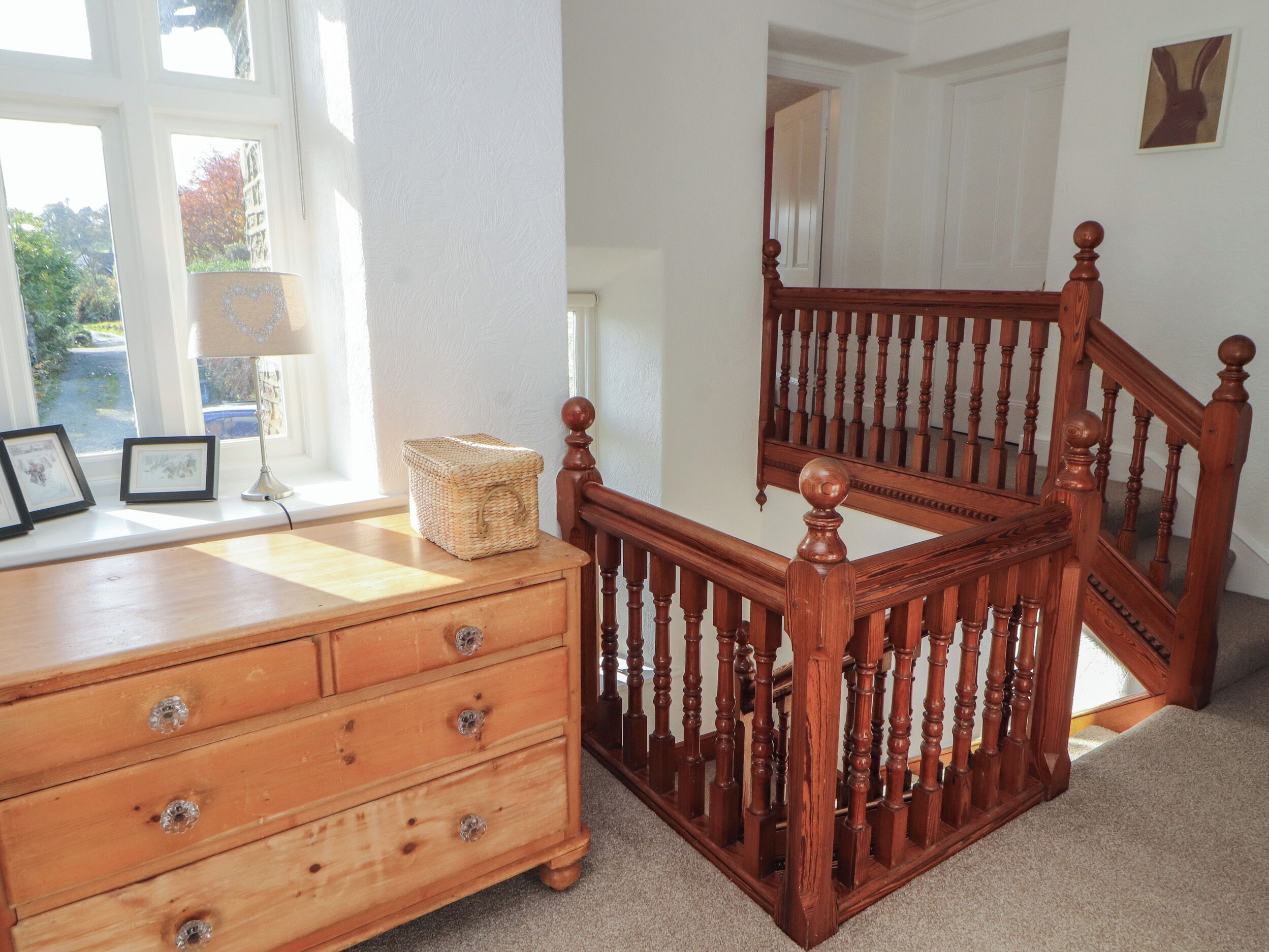A wooden staircase with a mirror, a wooden dresser with drawers, and a basket on top.