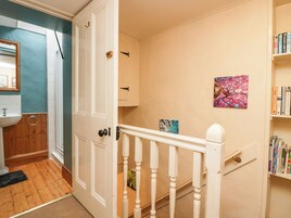 A hallway with a white door, a wooden floor, a sink, and a bookshelf.