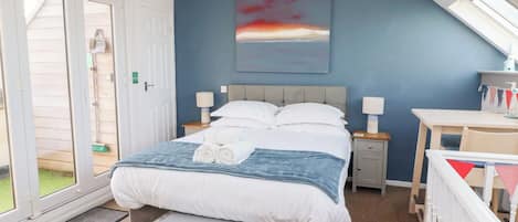 A bedroom with a bed, bedside tables, a desk, and a window.