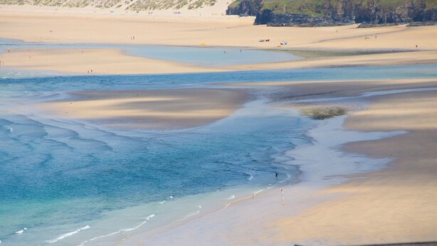 A coastal beach with multiple sandbars and calm waters.
