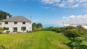 A house with a grassy yard and a view of the sea.