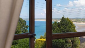 A view through a window of a coastal landscape with a beach, trees, and a clear sky.