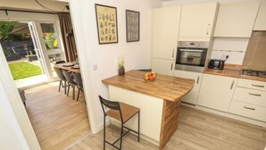 Una cocina moderna con suelo de madera, una isla central y armarios blancos.