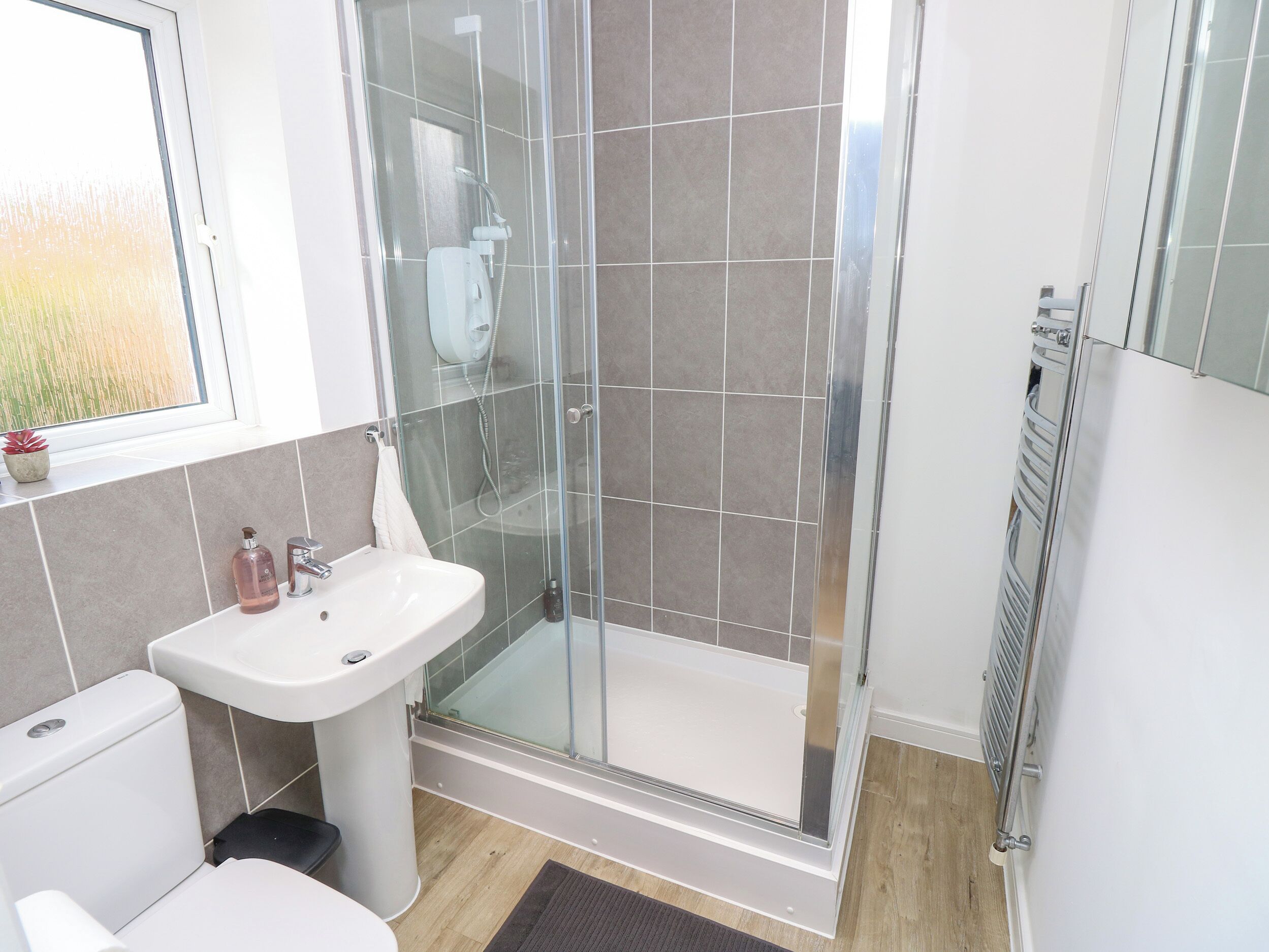 A modern bathroom with a glass-enclosed shower, a white sink, and a toilet.