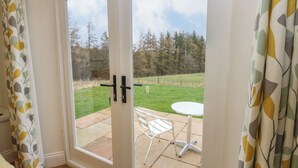 A room with a sliding glass door leading to an outdoor patio with a white table and chair. - Woodland View (Bishop Auckland)