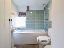 A bathroom with a bathtub, toilet, and a window.