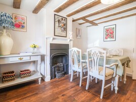A dining area with a fireplace, white chairs, and a table set for two.