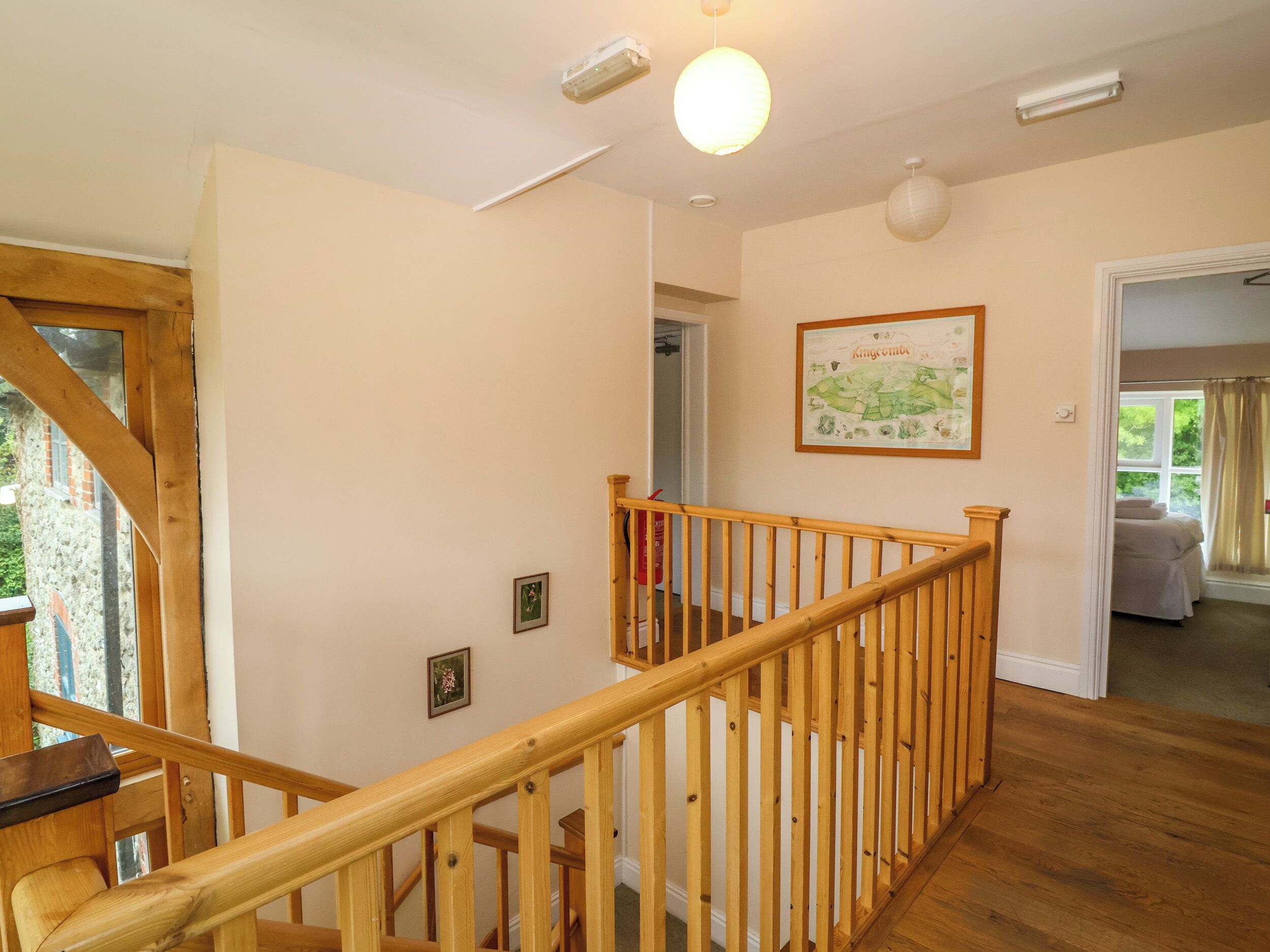 A wooden staircase with a railing leading to a bedroom with a bed and a window.