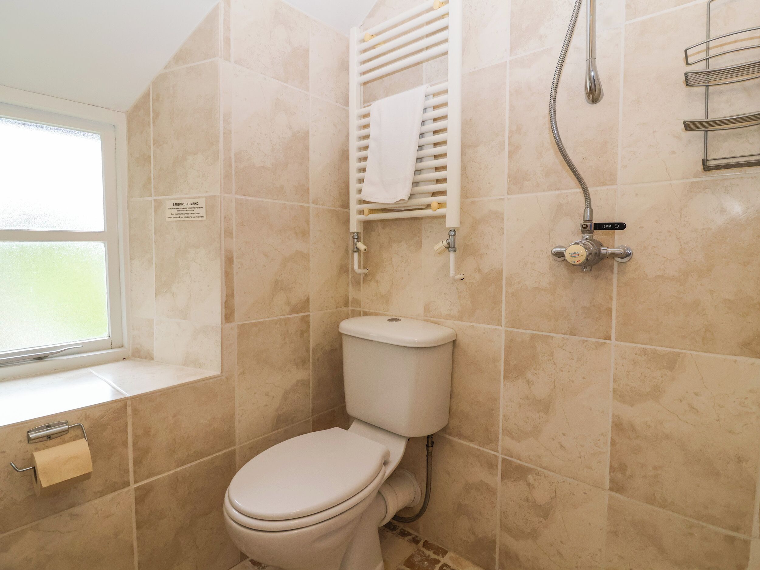 Une salle de bain avec des toilettes, une douche et une fenêtre.