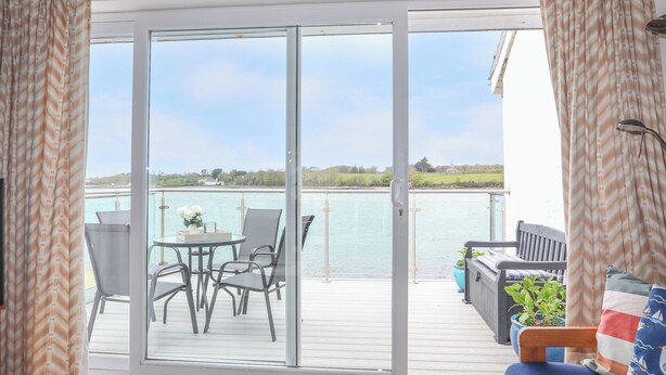 Un balcon avec une table et des chaises, une vue sur l’eau et une balustrade.